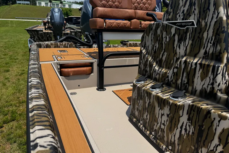 Slide: The Image of Avid 207 Recon 2026 boat with camo design and leather seating on grassy area. - 13