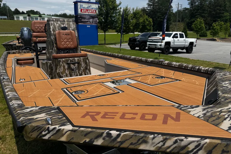 Slide: The Image of Avid 207 Recon 2026 boat with camo design and wood finish, parked outdoors. - 18
