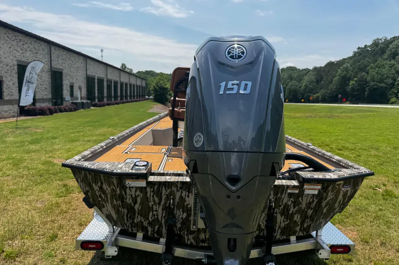 Slide: The Image of Avid 207 Recon 2026 boat with powerful 150 engine, parked on grass near a building. - 7