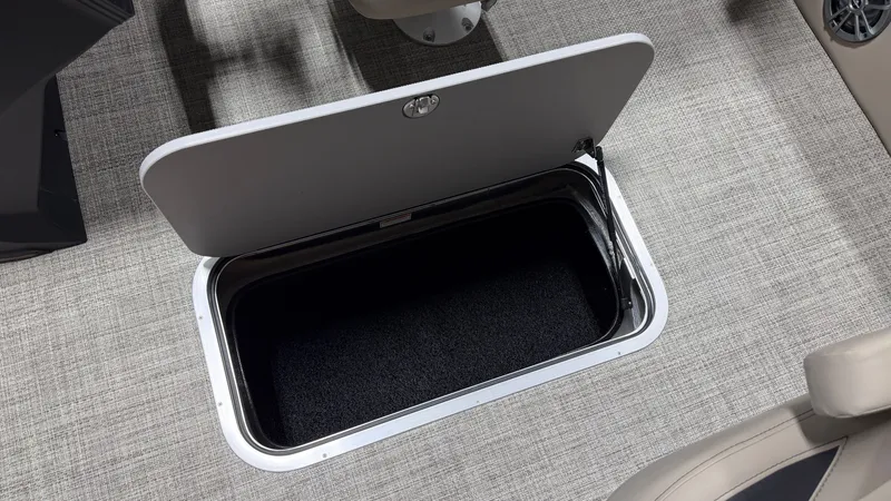 Slide: The Image of An open storage compartment on a boat with carpeted flooring and beige seating. - 37