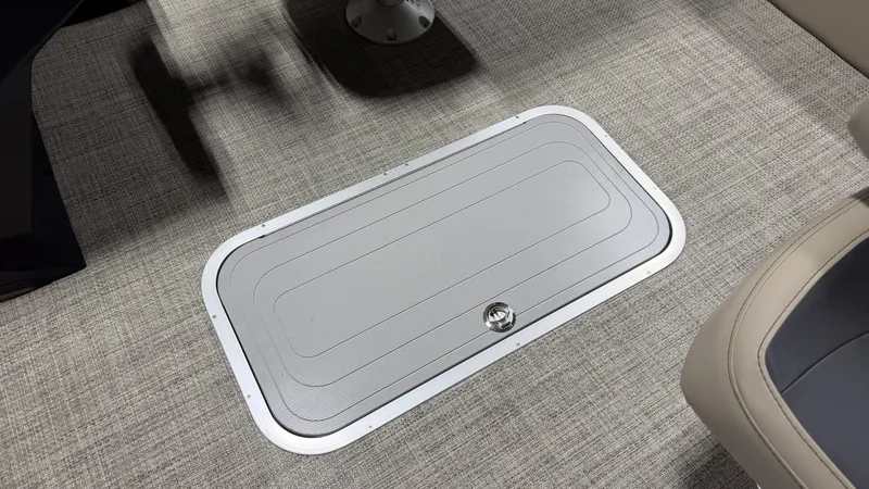 Slide: The Image of A gray floor hatch on a carpeted boat floor. A seat is partially visible. - 36