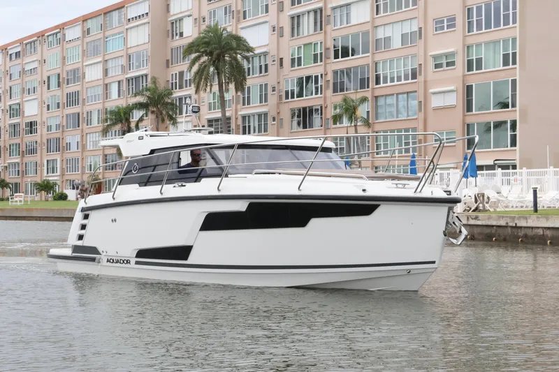 Slide: The Image of 2024 Aquador 300 HT boat cruising near waterfront apartments with palm trees. - 3