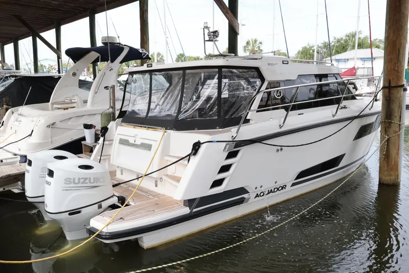 Slide: The Image of 2024 Aquador 300 HT boat docked with Suzuki engines, under a covered marina. - 66