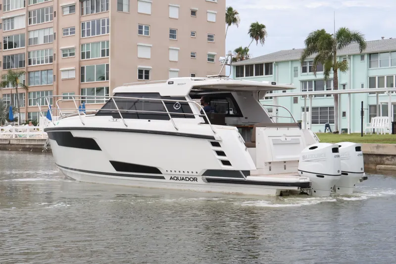 Slide: The Image of 2024 Aquador 300 HT boat cruising near waterfront buildings. - 7