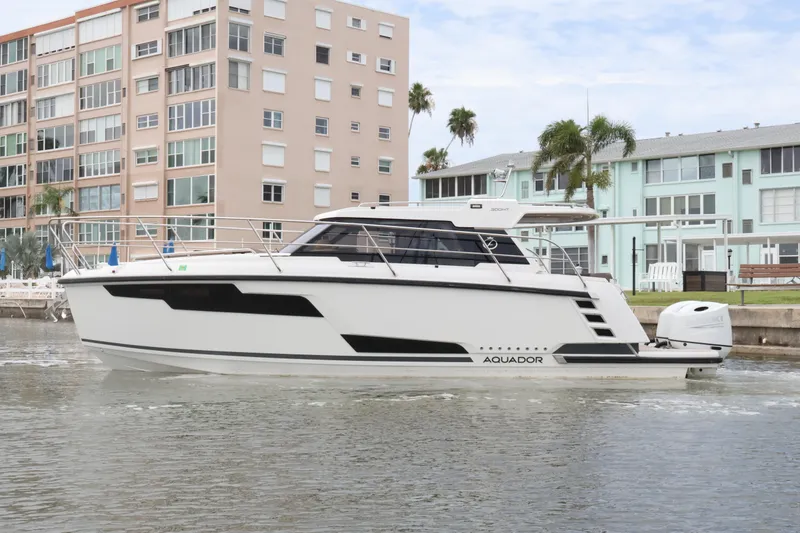Slide: The Image of 2024 Aquador 300 HT boat cruising near waterfront buildings. - 8