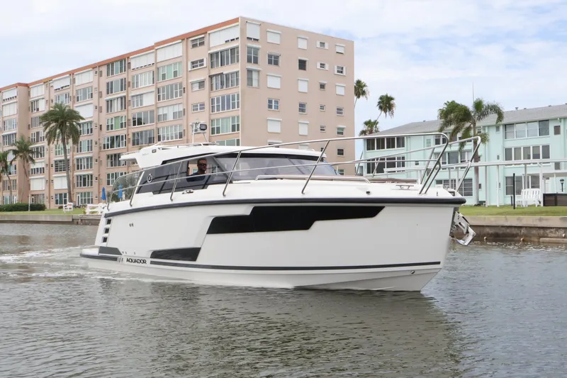 Slide: The Image of 2024 Aquador 300 HT cruising near waterfront buildings and palm trees. - 9