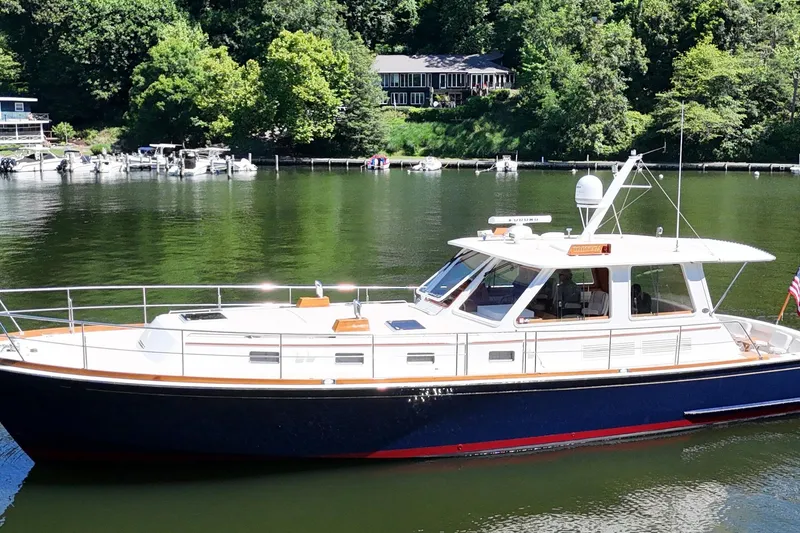 The Image of 2003 Grand Banks 49 Eastbay HX yacht on a serene lake with lush greenery. - 0