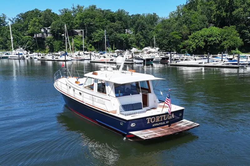 Slide: The Image of 2003 Grand Banks 49 Eastbay HX yacht docked in a scenic marina setting. - 1