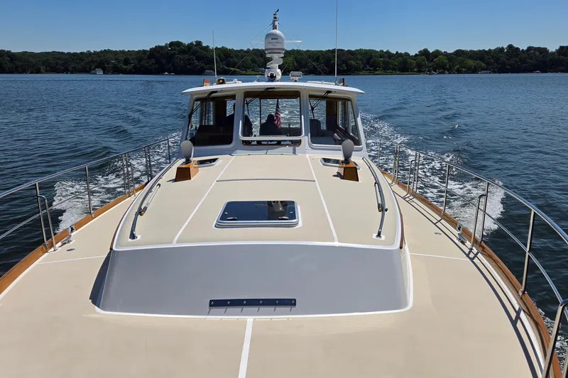 Slide: The Image of 2003 Grand Banks 49 Eastbay HX cruising on a serene lake under clear skies. - 13