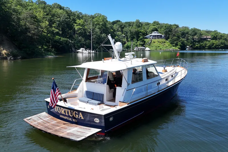 Slide: The Image of 2003 Grand Banks 49 Eastbay HX yacht on serene water with lush green backdrop. - 2