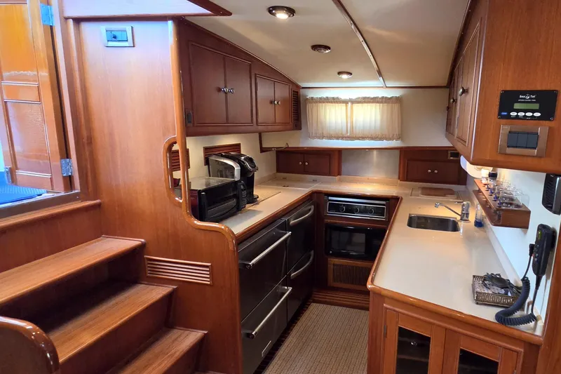 Slide: The Image of Luxurious 2003 Grand Banks 49 Eastbay HX yacht kitchen with wood cabinetry and modern appliances. - 31