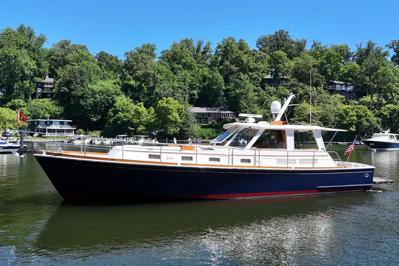 Slide: The Image of 2003 Grand Banks 49 Eastbay HX yacht on a serene lake with lush green surroundings. - 4