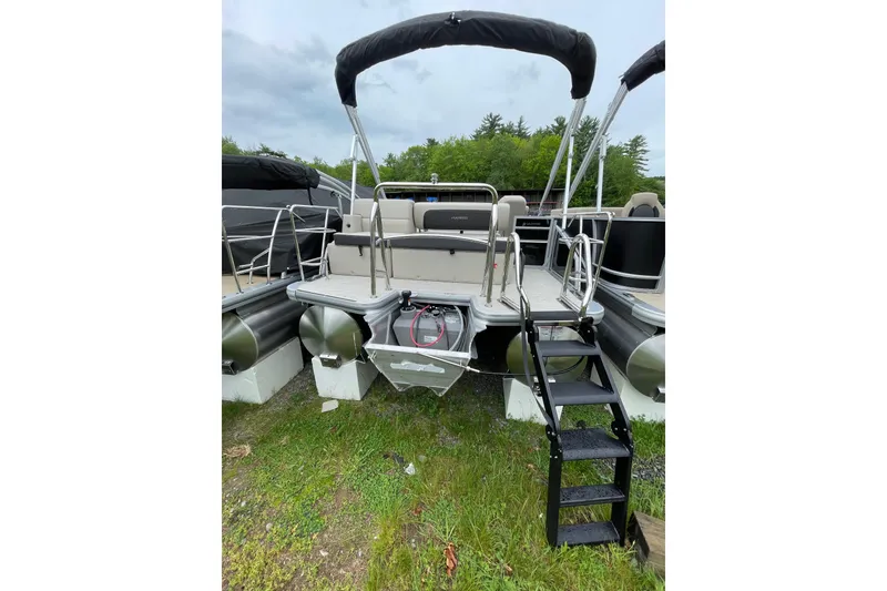 Slide: The Image of 2026 Harris Cruiser 230 SL pontoon boat with rear entry ladder and canopy, parked on grass. - 6