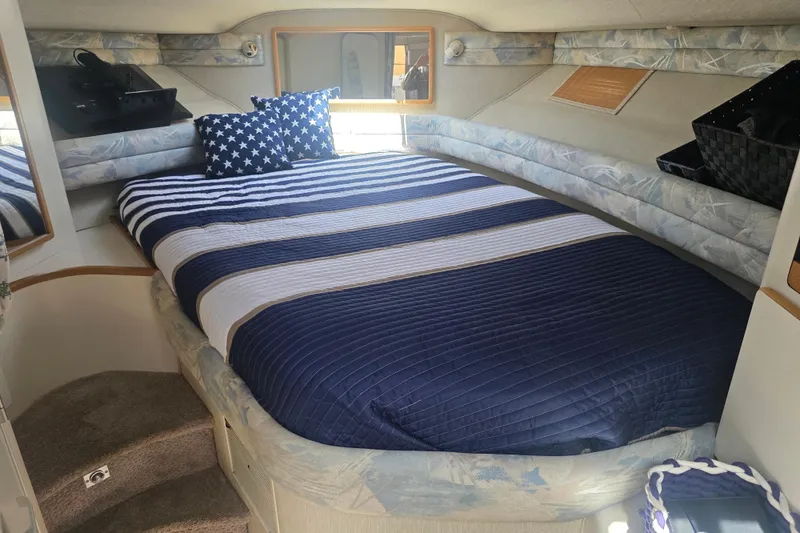 Slide: The Image of 1994 Sea Ray 370 Express Cruiser cabin with striped bedding and star-patterned pillows. - 16