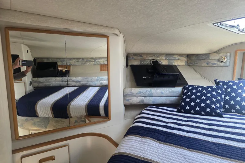 Slide: The Image of Interior of 1994 Sea Ray 370 Express Cruiser with striped bedding and mirrored closet. - 17