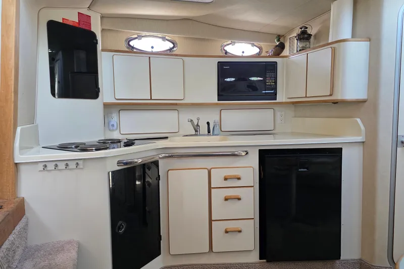Slide: The Image of 1994 Sea Ray 370 Express Cruiser kitchen with stove, microwave, and compact refrigerator. - 24