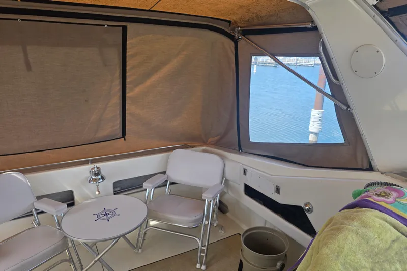 Slide: The Image of Interior of a 1994 Sea Ray 370 Express Cruiser with seating and table, overlooking marina. - 7
