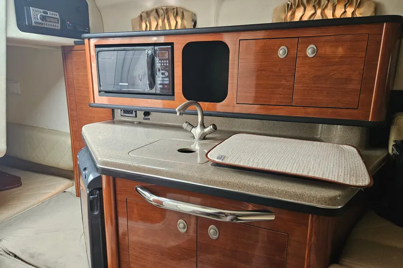 Slide: The Image of 2007 Sea Ray 270 Sundancer cabin kitchen with microwave, sink, and wooden cabinetry. - 6