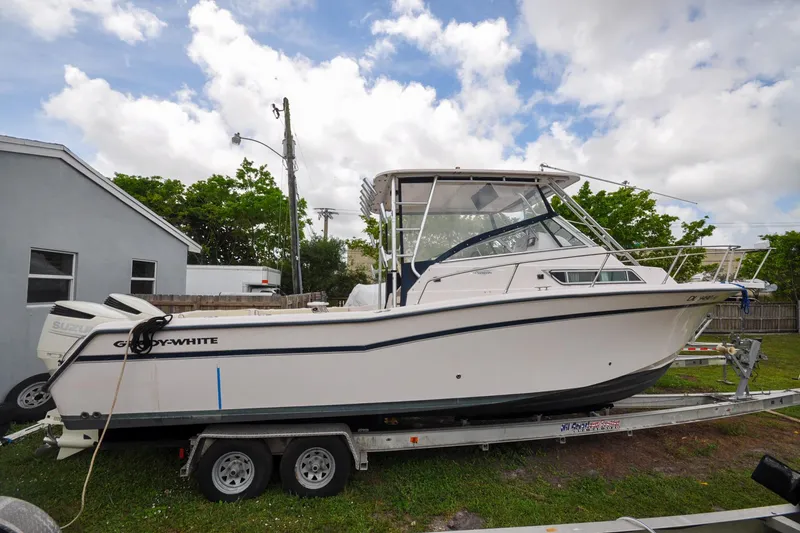Slide: The Image of 1997 Grady-White Marlin 300 boat on trailer, parked outdoors under cloudy sky. - 17