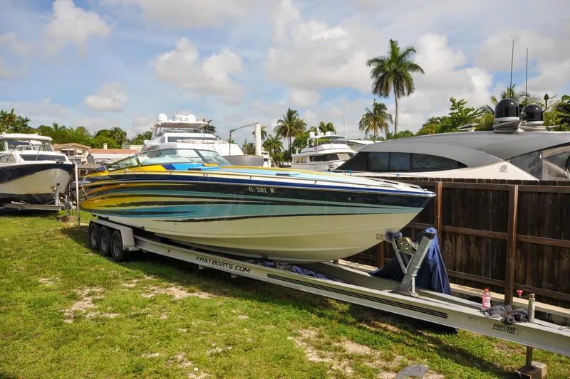 Slide: The Image of 2006 Formula 382 FASTech boat on trailer, vibrant colors, parked near yachts, palm trees in background. - 0