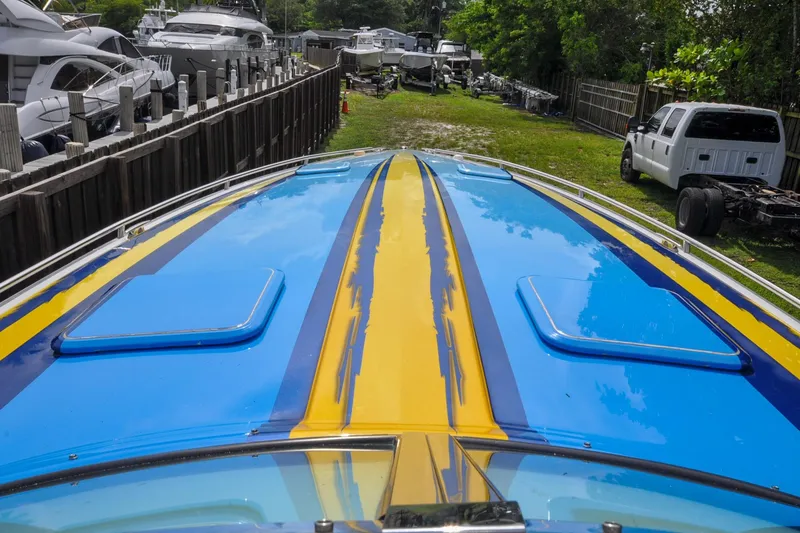 Slide: The Image of 2006 Formula 382 FASTech boat with vibrant blue and yellow design, docked near other vessels. - 14