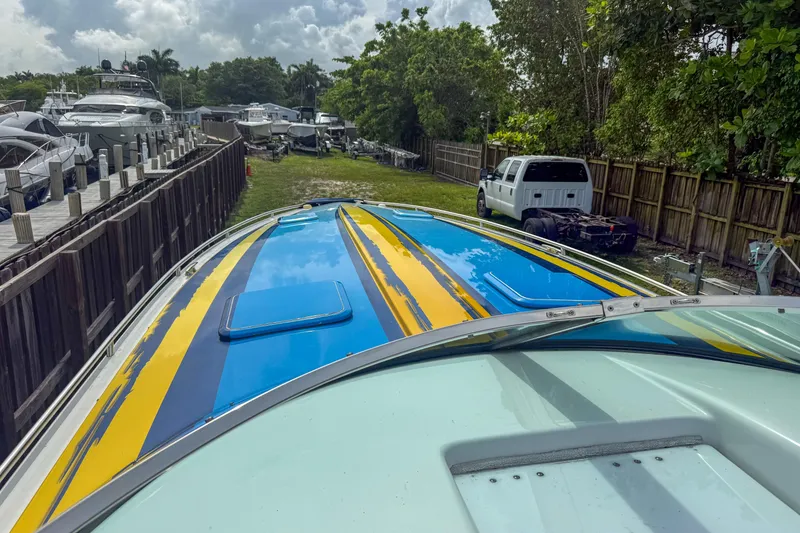 Slide: The Image of 2006 Formula 382 FASTech boat with vibrant blue and yellow stripes, docked near other vessels. - 15