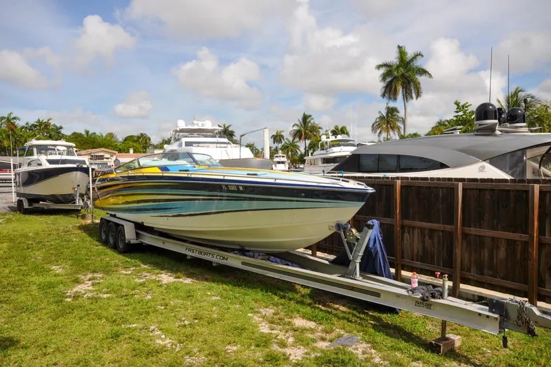 Slide: The Image of 2006 Formula 382 FASTech boat on trailer, parked near yachts, with palm trees in background. - 21