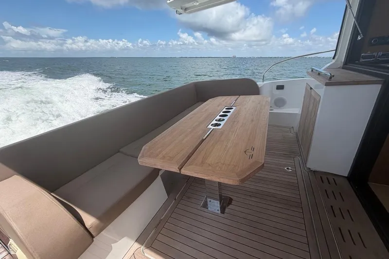 Slide: The Image of 2022 Sealine C430 yacht deck with wooden table, ocean view, and seating area. - 26
