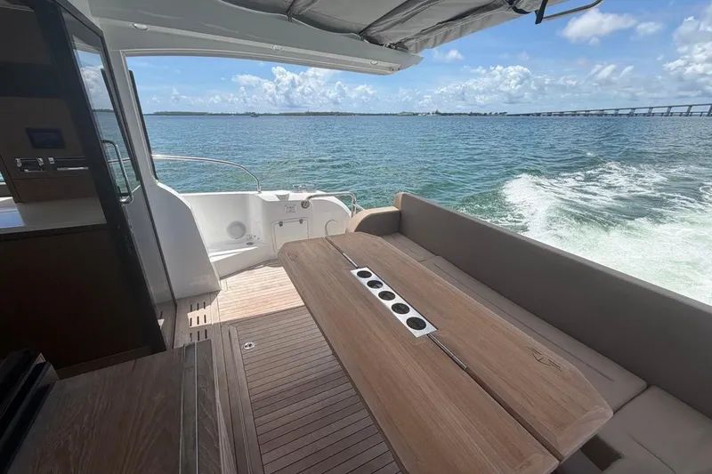 Slide: The Image of Sealine C430 2022 yacht interior with wooden table, ocean view, and sunny skies. - 27