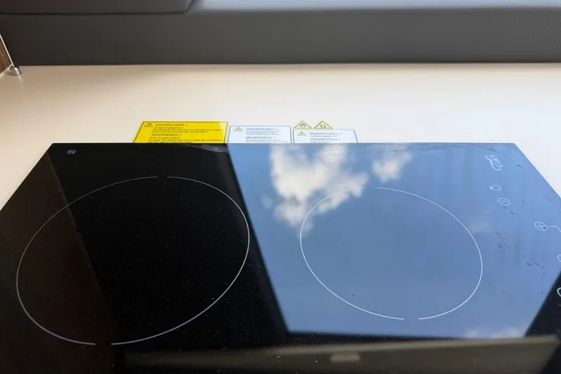 Slide: The Image of Modern induction cooktop on 2022 Sealine C430 yacht, reflecting sky and clouds. - 92