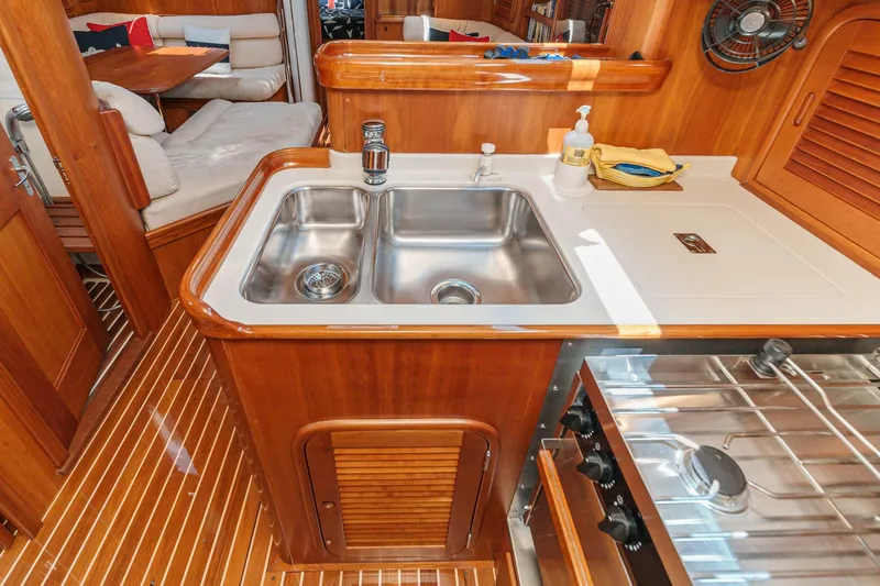 Slide: The Image of Hinckley Sou'wester 52 yacht interior, featuring a wooden galley with stainless steel sink and stove. - 48