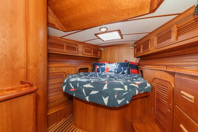 Slide: The Image of Hinckley Sou'wester 52 yacht cabin interior, featuring wooden finishes and nautical-themed bedding. - 64