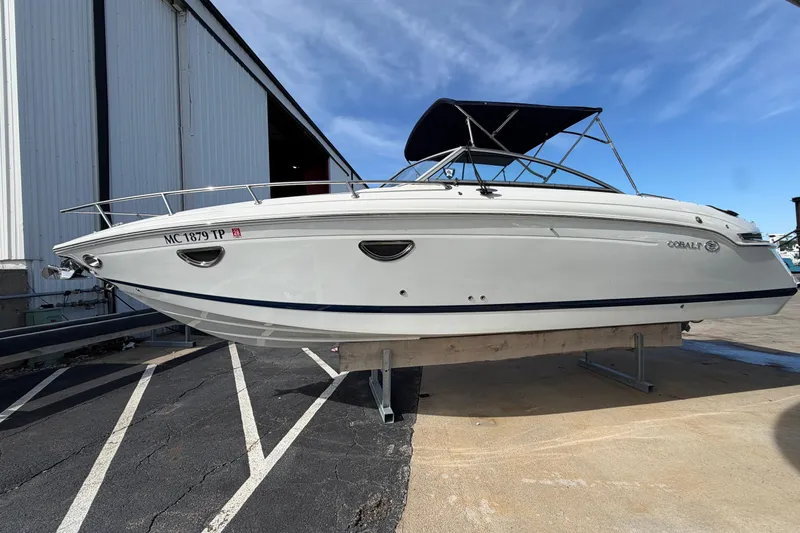 Slide: The Image of 2013 Cobalt 273 boat with canopy, parked on a stand near a building. - 0