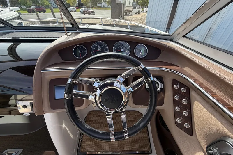 Slide: The Image of Steering wheel and dashboard of a 2013 Cobalt 273 boat, featuring gauges and controls. - 11