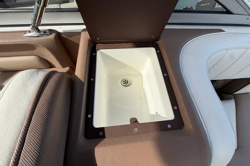 Slide: The Image of Open storage compartment on 2013 Cobalt 273 boat with brown and white upholstery. - 17