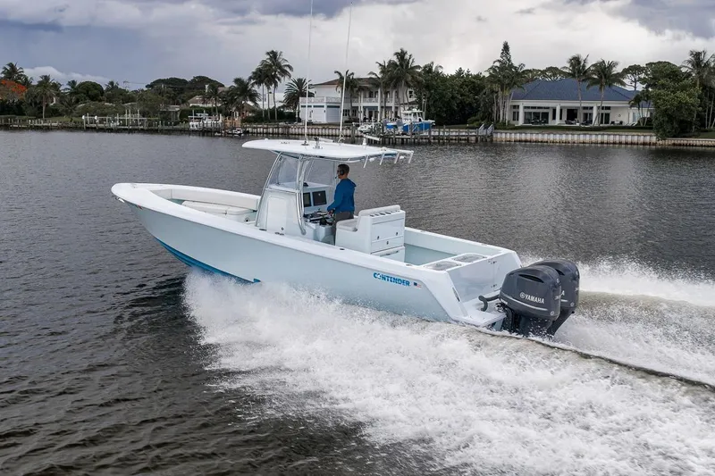 Slide: The Image of 2019 Contender 32 ST boat cruising on a scenic waterway with palm trees and houses. - 28