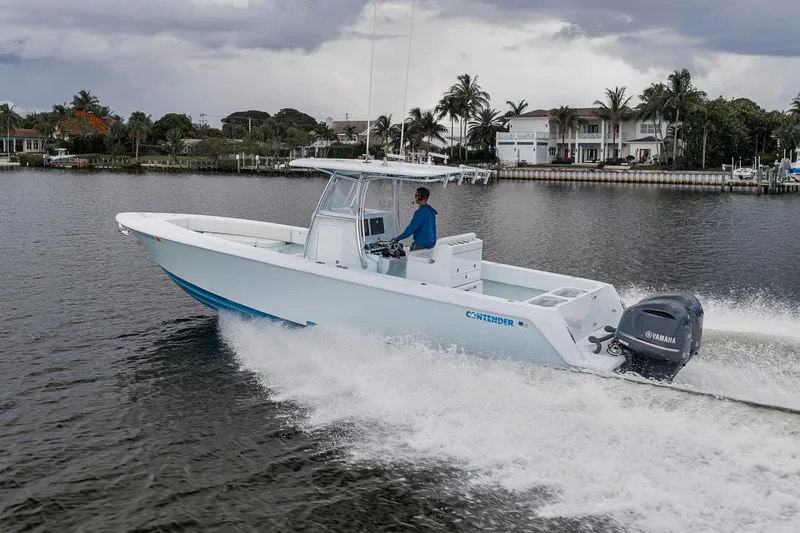 Slide: The Image of 2019 Contender 32 ST boat cruising on water with Yamaha engine, surrounded by waterfront homes. - 29