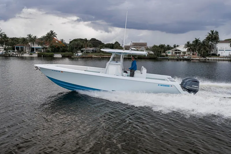 Slide: The Image of 2019 Contender 32 ST boat cruising on a scenic waterway with palm trees. - 30