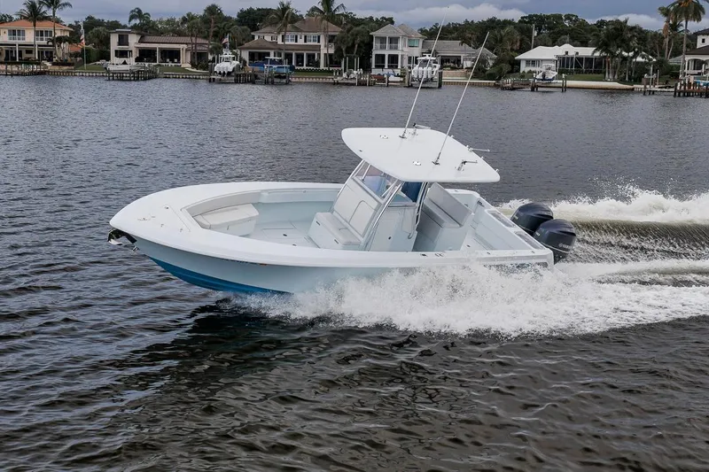 Slide: The Image of 2019 Contender 32 ST boat cruising on a scenic waterfront. - 32