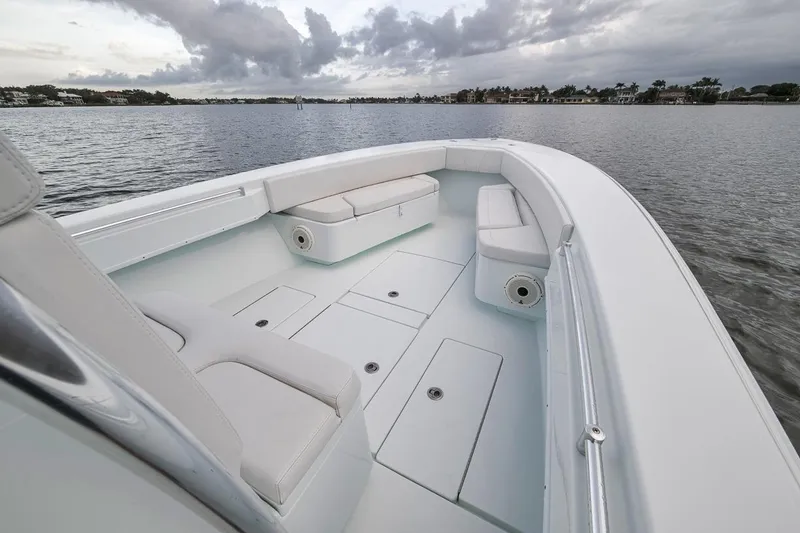 Slide: The Image of 2019 Contender 32 ST boat interior with white seating, on calm water under cloudy skies. - 44