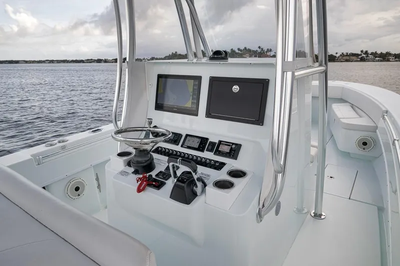 Slide: The Image of 2019 Contender 32 ST boat console with navigation screens and steering wheel on calm water. - 69