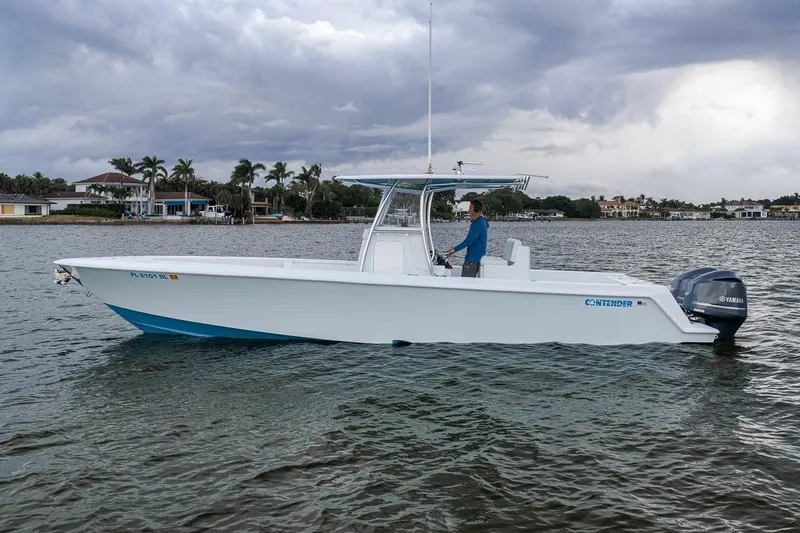 Slide: The Image of 2019 Contender 32 ST boat on water, overcast sky, person steering. - 7