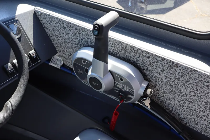 Slide: The Image of Throttle control panel of 2026 Alumaweld Talon 18 boat, featuring steering wheel and ignition keys. - 18