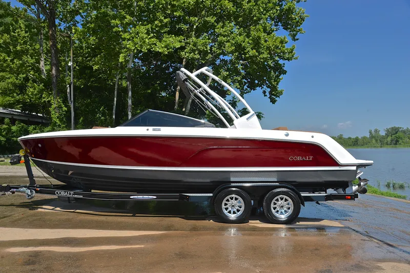 Slide: The Image of 2024 Cobalt CS23 boat on trailer by a lake, surrounded by trees. - 12