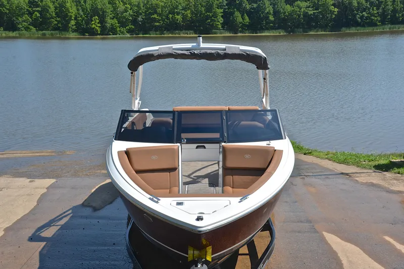 Slide: The Image of 2024 Cobalt CS23 boat on a ramp by a serene lake with lush greenery. - 18