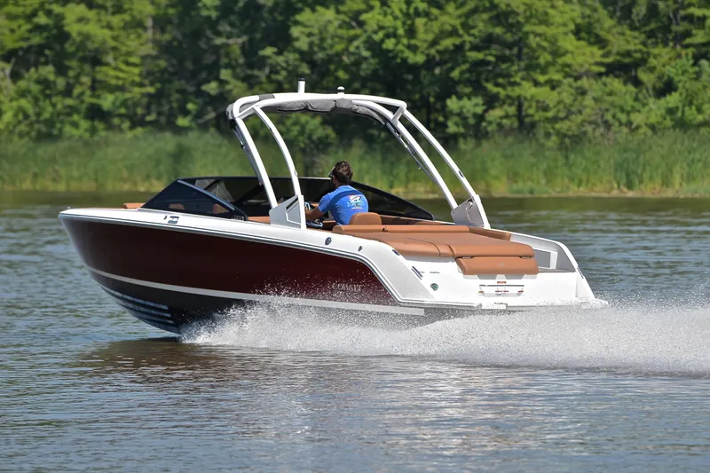 Slide: The Image of 2024 Cobalt CS23 boat cruising on a lake with lush green background. - 4