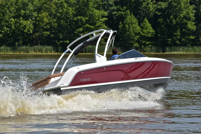 Slide: The Image of 2024 Cobalt CS23 boat cruising on a lake with lush green trees in the background. - 5