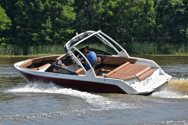 Slide: The Image of 2024 Cobalt CS23 boat cruising on a lake with lush green trees in the background. - 6