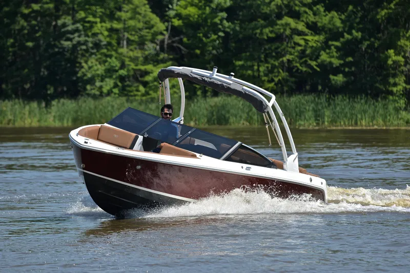Slide: The Image of 2024 Cobalt CS23 boat cruising on a lake with lush green trees in the background. - 7