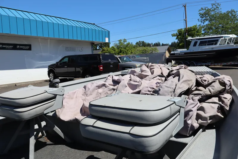 Slide: The Image of 2003 Alumaweld Flatbottom boat with covered seats, parked near a blue-roofed building. - 15
